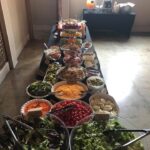 A long table with a variety of salads on it.