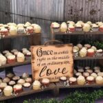 Cupcakes on a wooden stand with a sign.