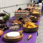 A purple table with a variety of food on it.