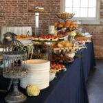 A buffet is set up in a room with a brick wall.