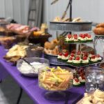 A purple table with a variety of food on it.