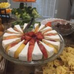 A buffet with a variety of cheeses, fruits, and breads.