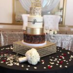 A gold and black wedding cake on a table.