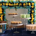 A dessert table with blue and yellow flowers.