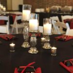 A black and red table setting with candles and silverware.