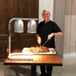 A woman standing in front of a table with food on it.