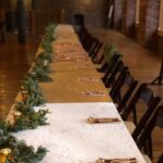 A long table set up with greenery and candles.