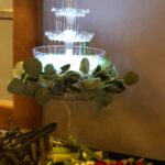 A table with a fountain and vegetables on it.