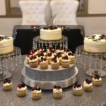 A table with several cakes and cupcakes on it.