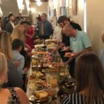 A group of people standing around a long table.