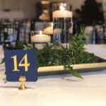 A table with candles and greenery on it.