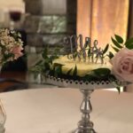 A wedding cake and flowers on a table.