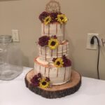 A wedding cake with sunflowers on top.