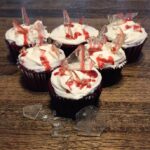 A group of cupcakes with red velvet frosting and shards of glass.