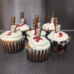 A group of cupcakes with a knife on top.