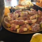 A plate of fruit and ham on a table.