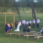 A wedding ceremony in a field with benches.