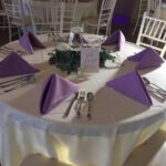 A table setting with purple napkins and silverware.