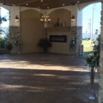 A stone patio with a fireplace and flowers.