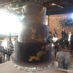 A black and gold wedding cake on a table.