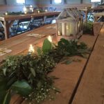 A wooden table with greenery and candles on it.