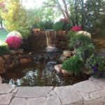 A pond with a waterfall in the middle of a yard.