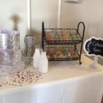 A table with a cake, cookies, and confetti.