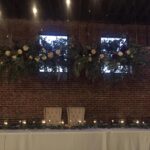 A table set up with flowers and candles in a brick building.