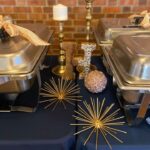 A table with silver trays and candles on a blue tablecloth.