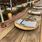 A table setting with gold plates and napkins on a wooden table.