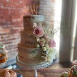 A wedding cake and donuts on a wooden table.