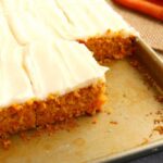 Carrot cake bars with icing on a baking sheet.