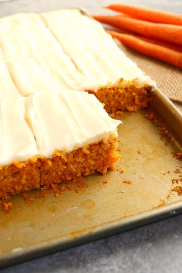 Carrot cake bars with icing on a baking sheet.