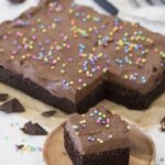 A slice of chocolate cake with sprinkles on a plate.