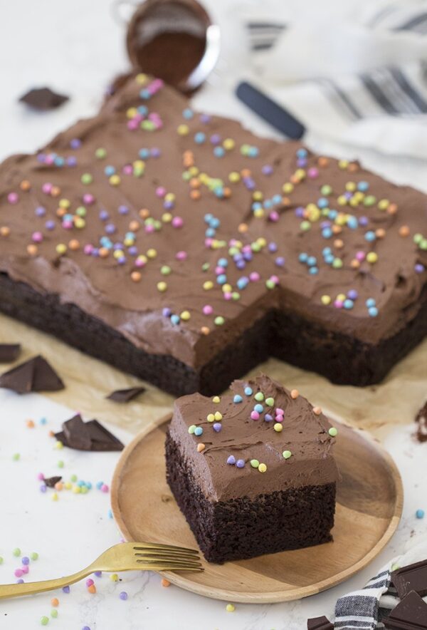 A slice of chocolate cake with sprinkles on a plate.