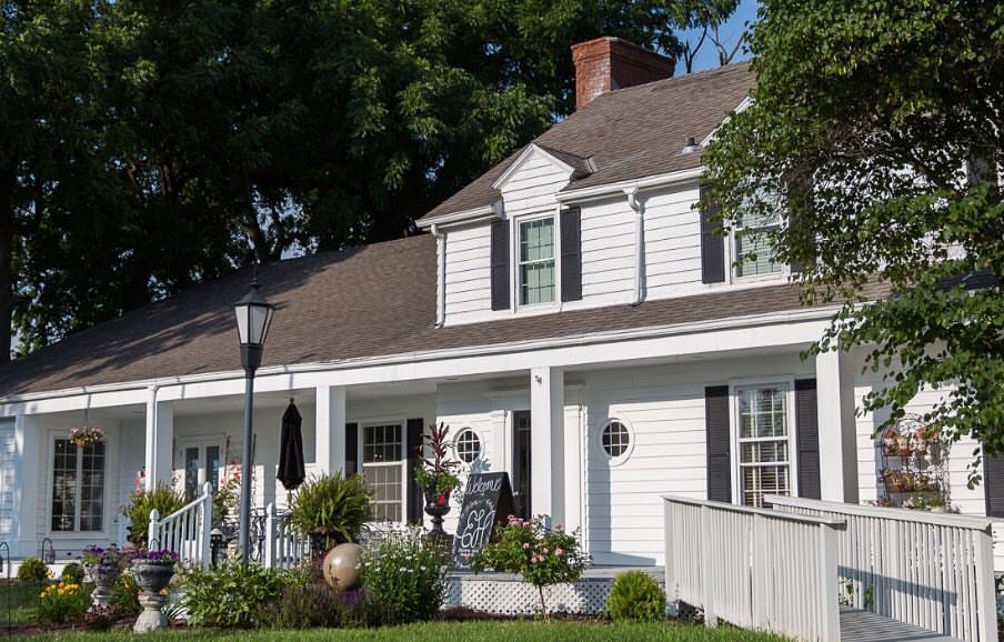 A white house with a porch and landscaping.