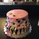 A pink and black cake decorated with flowers and zebra stripes.