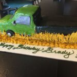 A birthday cake with a green truck on it.