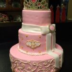 A pink cake with a princess tiara on top.