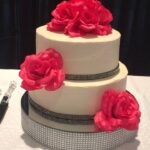 A white cake with pink flowers on top.