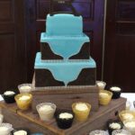 A wedding cake with cupcakes on a wooden stand.