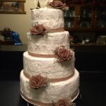 A three tier wedding cake with brown roses on top.