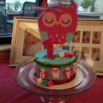 A pink cake with an owl on top.