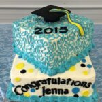 A cake with a graduation cap and hat on top.