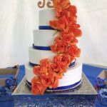 A three tier wedding cake with orange roses.