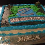 A blue cake with the words jurassic world on it.