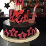 A pink and black cake decorated with stars and a guitar.