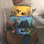 A three tier cake with a deer on top.