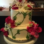 A white cake with pink flowers on top.