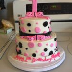 A pink and black cake with polka dots on top.